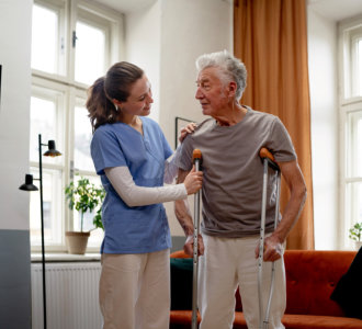 elderly in crutches assisted by his caregiver