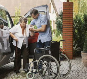 aide assisting the senior woman getting out of the car