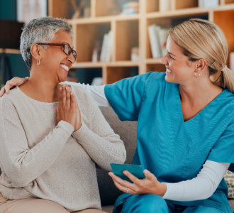 A caregiver and an elderly woman sitting on a couch