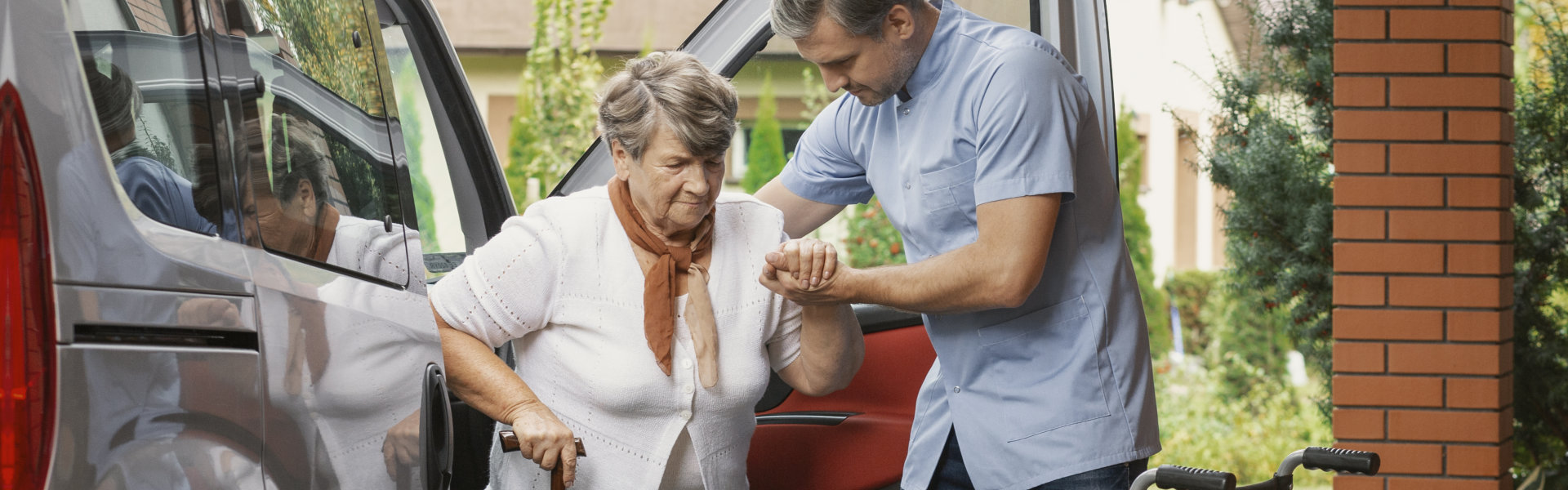 aide assisting the senior woman getting out of the car
